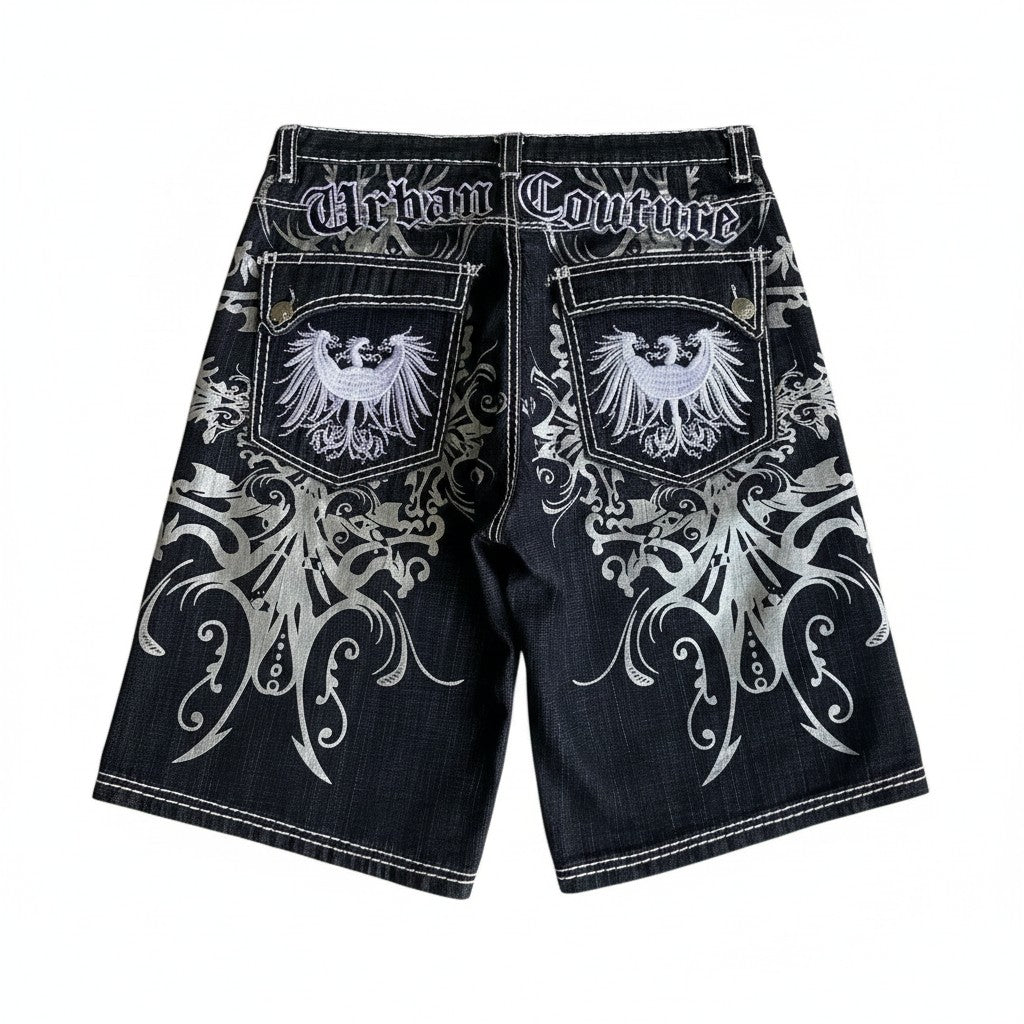 AuraXclusive black denim shorts featuring gothic white embroidery, eagle motifs on back pockets, and loose streetwear fit.
