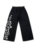 AuraXclusive black loose-fit denim jeans featuring intricate white floral embroidery on the right leg.