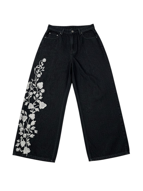 AuraXclusive black loose-fit denim jeans featuring intricate white floral embroidery on the right leg.