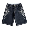 AuraXclusive dark denim shorts with intricate silver embroidery and white contrast stitching in a loose hip hop style.