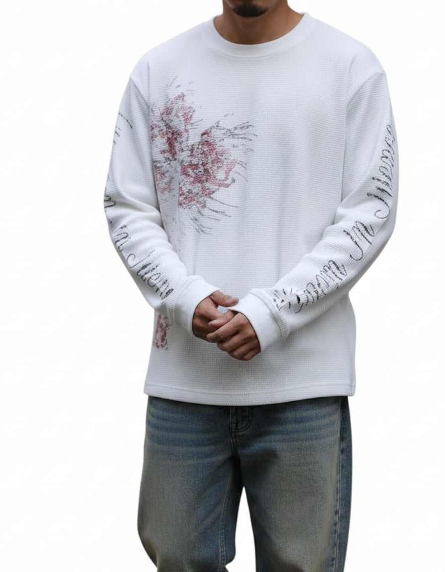 AuraXclusive white long-sleeved waffle knit top with Y2K-inspired graphic print and script lettering on the sleeves.