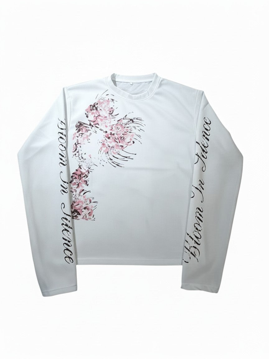 AuraXclusive white long-sleeved waffle knit top featuring a floral print and Bloom In Silence text on the sleeves.
